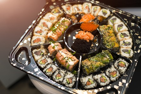 Sushi Set nigiri and sushi rolls on wooden serving board with soy sauce and chopsticks over black stone texture background. Top view with space. Japan menuの写真素材