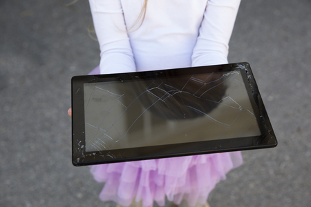 Woman picking up and holding cracked screen smart phone from the groundの写真素材