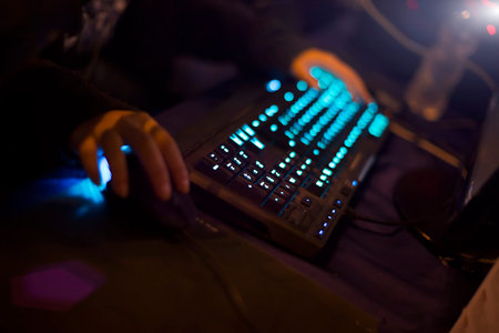 Young man playing video game with laptop. Gamer with computer in dark or late at night. Hands on...