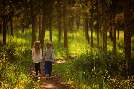 Two girls running in the forest holding handsの写真素材