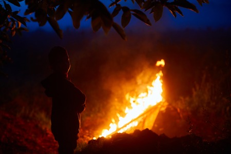 Silhouette of a boy in the background of a burning fire.の写真素材