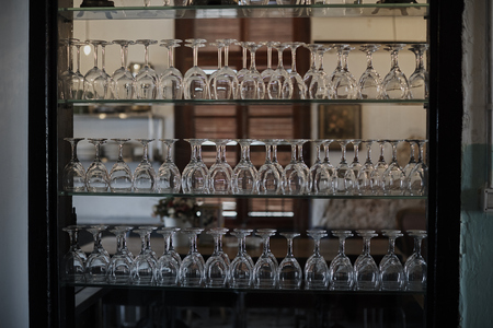 Wine glasses in a brown closet illuminated by the evening sun.の写真素材