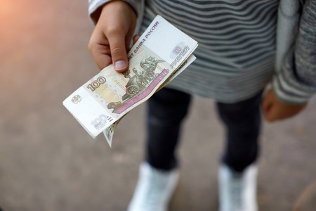 Male hand opening a white envelope full of Russian currency Russian Ruble, RUB on the wooden table as a symbol of cash transfer, money laundering or bribery in Russiaの写真素材