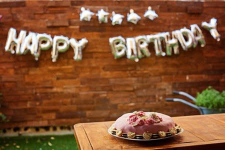 Birthday party with pink birthday cake on a wooden background and inscription happy birthday.の写真素材