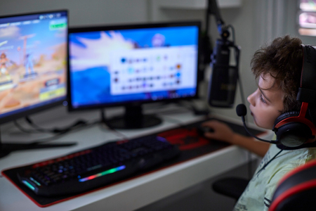 professional computer player plays on a computer using two monitorsの写真素材