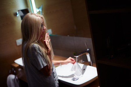 Frightened woman standing in the tub behind the curtain. Scared girl cover her mouth with palm. Horror in bathroom.の写真素材