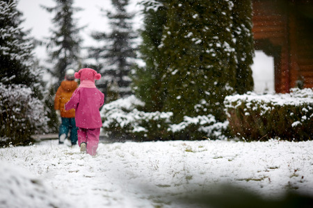 two children are on the snow-covered road, rear viewの写真素材