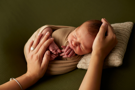 From above shot of hands of anonymous mother gently touching sleeping infantの写真素材