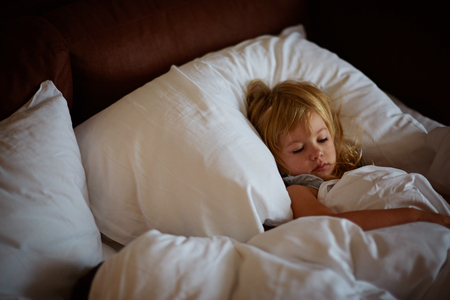 Cute little blond caucasian girl awakening at bed in morning. Child wake up early to go to school. Stretching and yawning. Healthy sleeping. Children healthcare.の写真素材
