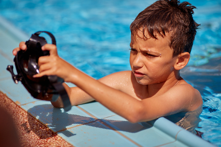 Teenager boy wearing mask swimming in the pool. Happy holiday concept. Cute happy little boy swimming and snorking in the swimming pool.の写真素材