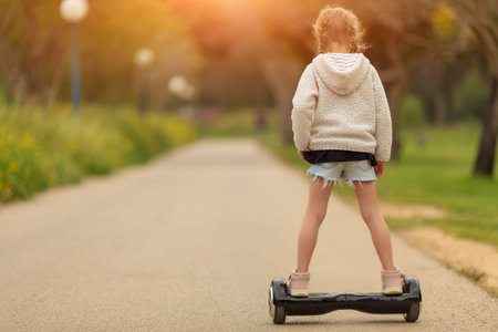 Child on hoverboard. Kids riding scooter in summer park. Balance board for children. Electric self...
