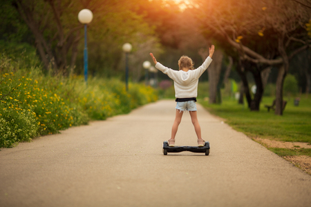 little girl riding a electric scooter . Personal eco transport ,gyro scooter,smart balance wheelの写真素材