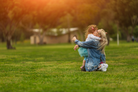 Mom and daughter laugh and hug in the park in summer. Tenderness and loveの写真素材