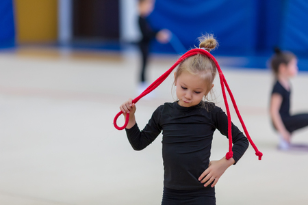 little gymnast is holding the rope over her head while exercisingの写真素材