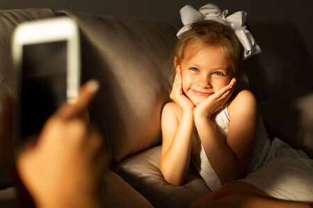 mom takes a picture of her daughter using a phone in low lightの写真素材