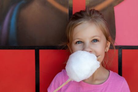 Adorable little girl eating candy floss outdoors at summerの写真素材