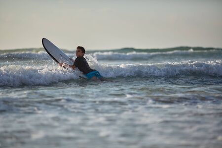 guy conquers the waves on the surfboardの写真素材