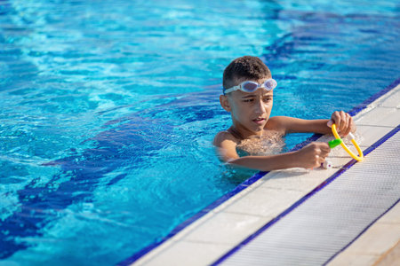 kid doing sports and swimming underwater in the pool on a blue background with toys in his hands
