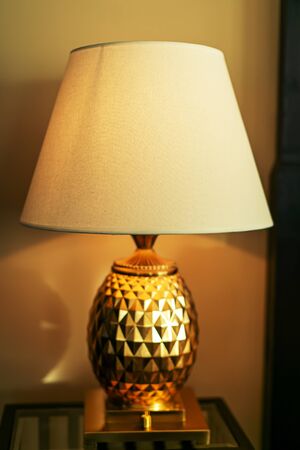 Luxurious golden lamp shade lit in a roomの写真素材