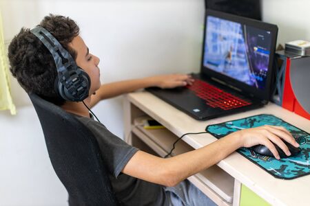 Little dependent gamer boy playing on laptop at homeの写真素材