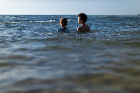 brother and sister in the beach at sunsetの写真素材