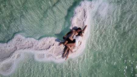 couple of tourists rest and lie in an embrace on the shore of the Dead Seaの写真素材