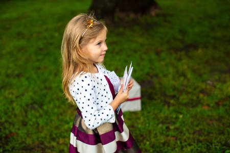 little girl with a crown on her head in festive clothes holds gift envelopes in her handsの写真素材