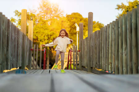 blonde child girl running on wooden bridge with sunlightの写真素材