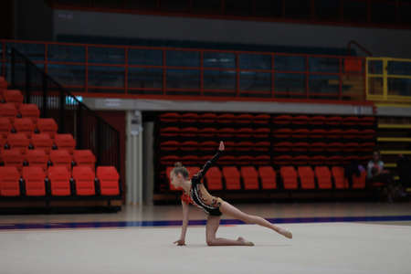 Young cute woman in gymnast suit show athletic skill. Empty sports stadium seatsの写真素材