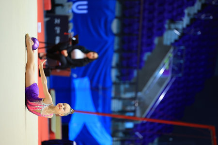gymnastics and ball between legs of performance, competition training or dancing in dark sports arena. Female athlete, rhythmic movement and creative talent in solo concert, agility or balanceの写真素材