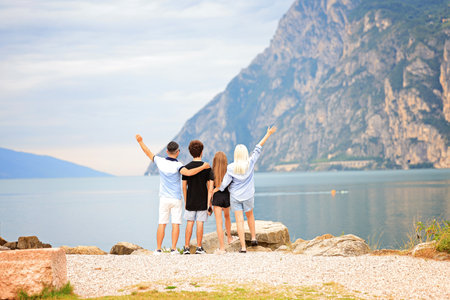 Friends enjoying a scenic view by a tranquil lake Garda Italia, surrounded by majestic mountainsの写真素材