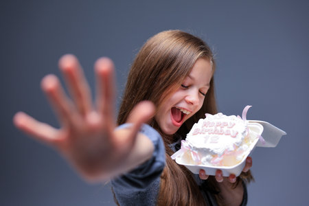 Joyfully Celebrating with Cake A Delightful Girl Enjoying Her Delicious Dessert Optionの写真素材