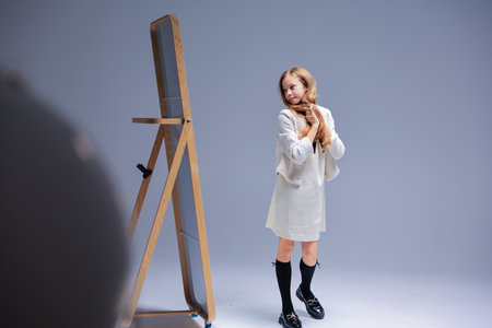 A captivating portrait of a young girl in a studio, showcasing her mirror reflectionの写真素材
