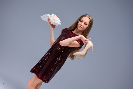 A Fashionable Young Girl, wearing High Heels, joyfully holding gifts in her handsの写真素材
