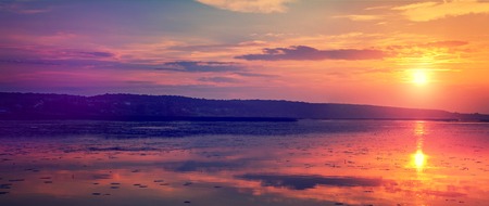 Sunset over the lake. colorful clouds in the sky, reflected in the waterの写真素材