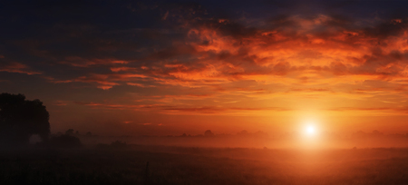 majestic dramatic scene. fantastic foggy sunset over the meadow with colorful clouds on the sky. picturesque rural landscape, misty morning. color in nature. beauty in the worldの写真素材