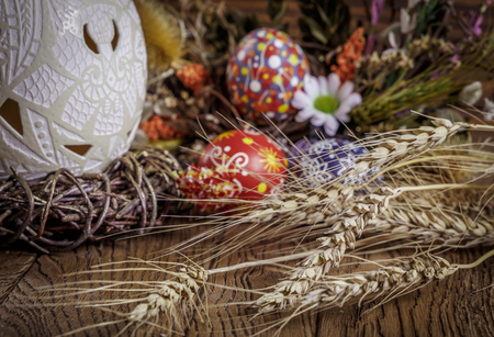 Easter background. colored Easter eggs, ostrich egg in the nest and composition of dried flowers, plants and ears of wheat. on wooden background.small depth of field. Easter theme. Happy Easterの写真素材
