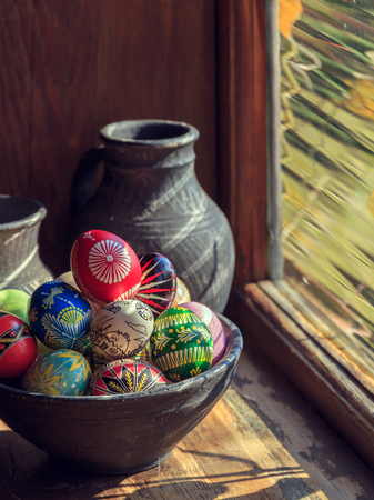 Easter eggs in a clay plate. lit by the sun from the window. wooden texture. Easter background. happy Easter.の写真素材