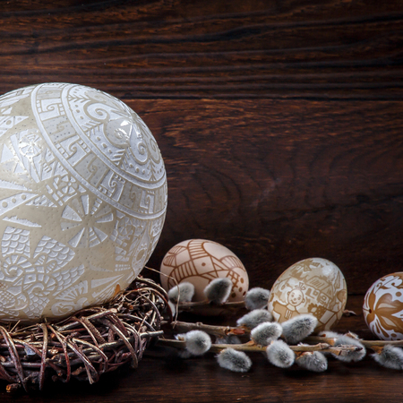 Decorative hand-painted Easter eggs. in a nest decorated ostrich egg on a wooden table. willow branches with blossoms. easter themed. Happy Easterの写真素材