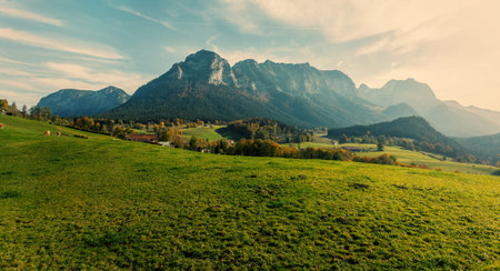 Amazing landscape in the Alps with  fresh green meadows under Sunlight in Warm Sunset. typical...
