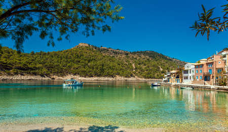 Amazing coastline with colorful houses under sunlight. Wonderful summer seascape with perfect blue sky of Ionian Sea. Assos village. Kefalonia. Greece.の写真素材