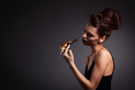 Woman with snail with black eyes and lips in Gothic Halloween imageの写真素材