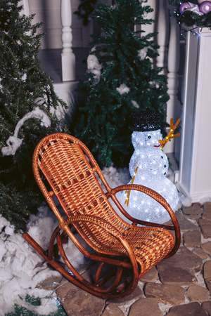 Wicker rattan chair, in a Christmas interior with a snowman and Christmas treesの写真素材