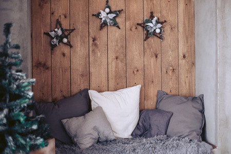 Bed with pillows with New Year's attributes on the background of a natural wooden panelの写真素材