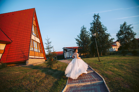 The bride in a white dress is walking along the path to the banquet hallの写真素材