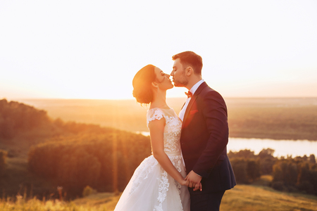 Bride and groom kissing in nature during wedding ceremonyの写真素材