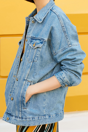 Stylish feminine look from a denim jacket and a yellow skirt with diagonal lines. Side view, on the left. Street style.の写真素材