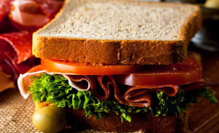 Close-up photo of a club sandwich. Sandwich with meat, prosciutto, salami, salad, vegetables,...