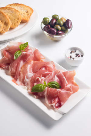 Closeup of thin slices of prosciutto with mixed olivesの写真素材