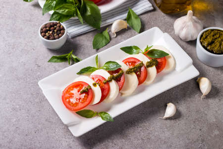 Close-up photo of caprese salad with ripe tomatoes, basil, buffalo mozzarella cheese. Italian and Mediterranean food concept. Fresh and healthy organic meal. Starter and antipasti.の写真素材